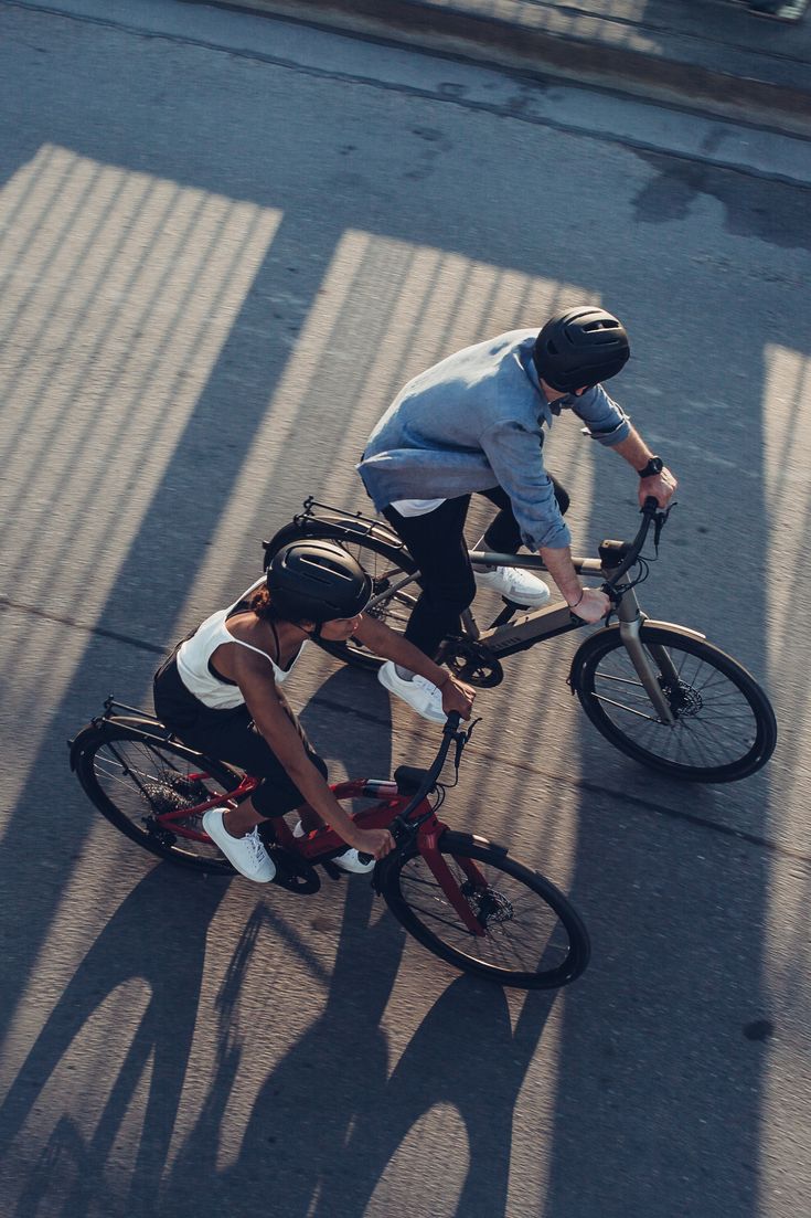 two bicyclists are riding down the street together