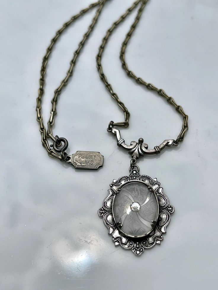 Beautiful antiqued sterling silver setting holds a vintage czech cut glass cabochon with a crystal rhinestone in center.  Attached to sterling silver on a 19" antiqued sterling chain. Originally designed by Pididdly Links in the 1970's. A rare finding. Victorian Antique Silver Nickel-free Necklace, Victorian Jewelry With Oxidized Metal Finish, Victorian Oxidized Metal Jewelry, Elegant Pewter Necklace As Gift, Elegant Pewter Necklace As A Gift, Elegant Pewter Necklace For Gift, Antique Silver Necklaces With Oval Vintage Charm, Antique Silver Necklace With Vintage Charm, Silver Vintage Charm Oval Pendant Jewelry