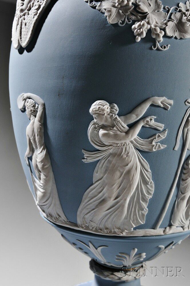 an ornate blue vase with white designs on the bottom and sides, depicting two women