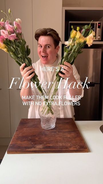 a man holding flowers up to his face while standing in front of a counter top