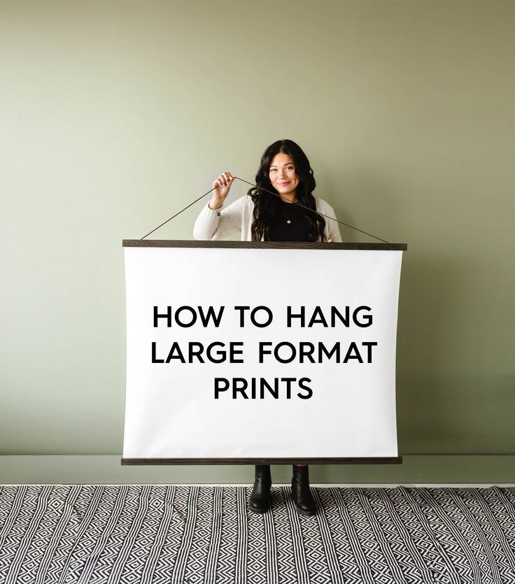 a woman standing behind a sign that says how to hang large format prints