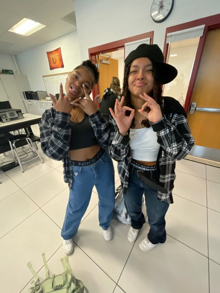 two young women standing next to each other making the v sign with their hands in front of them