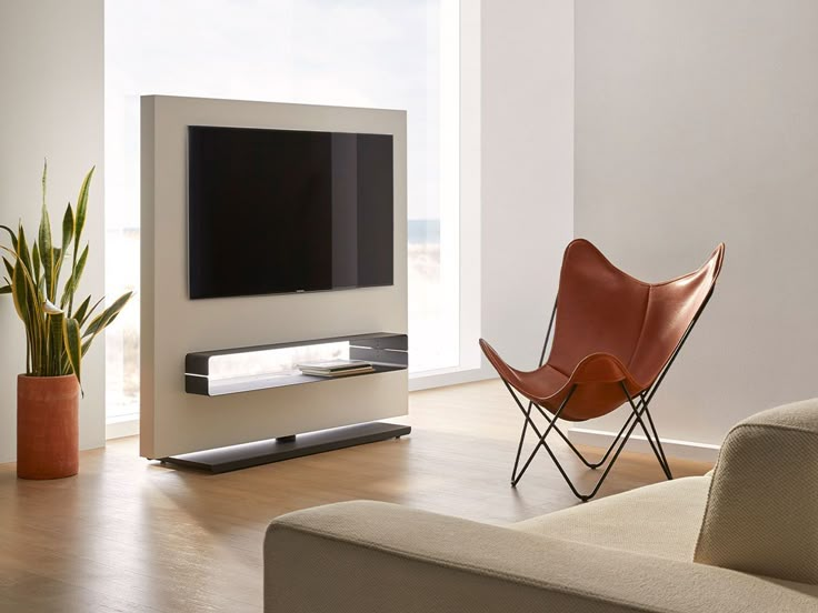 a living room with a couch, chair and flat screen tv on the wall next to a potted plant