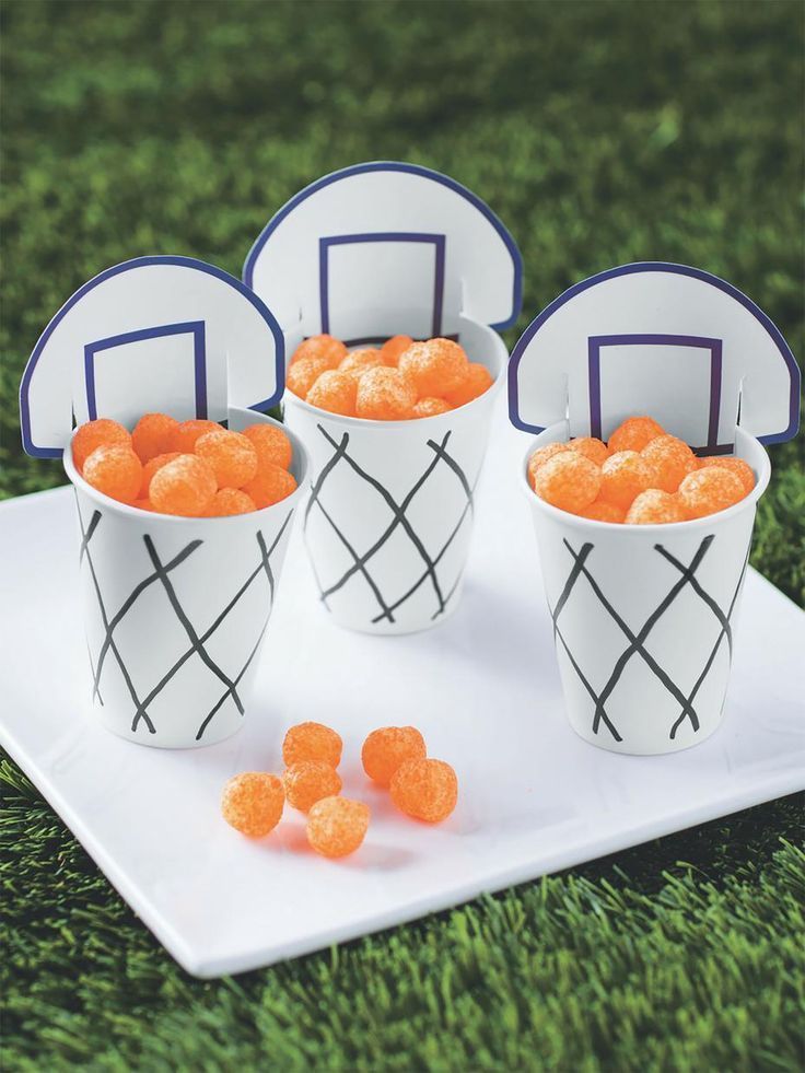 four paper cups filled with oranges on top of a white plate in the grass