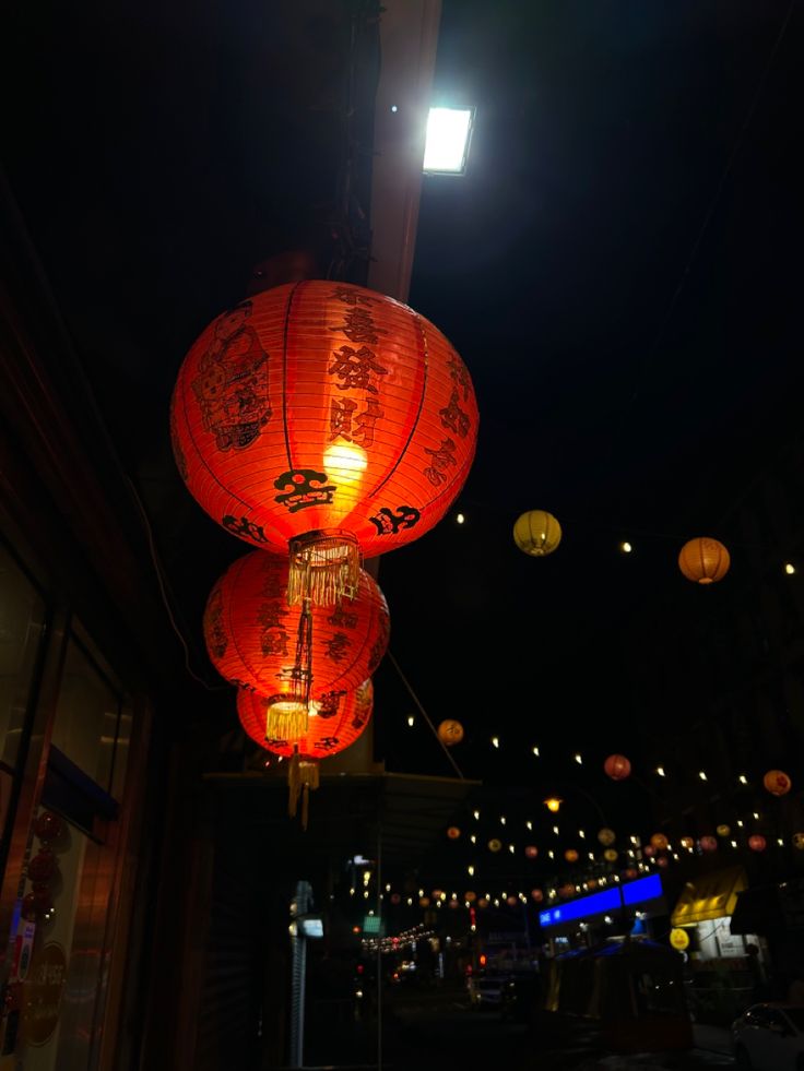 three red lanterns hanging from the ceiling at night