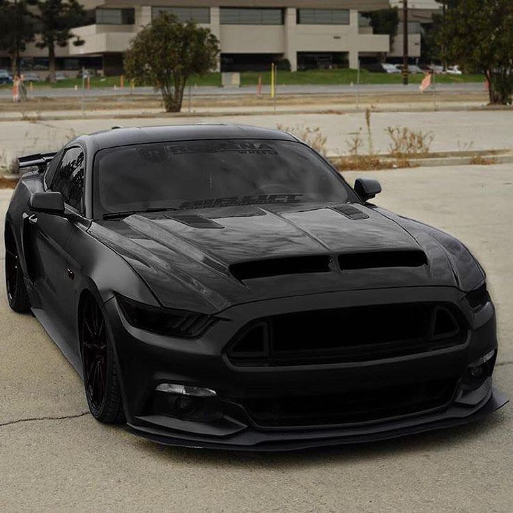 a black sports car parked in front of a parking lot next to a large building