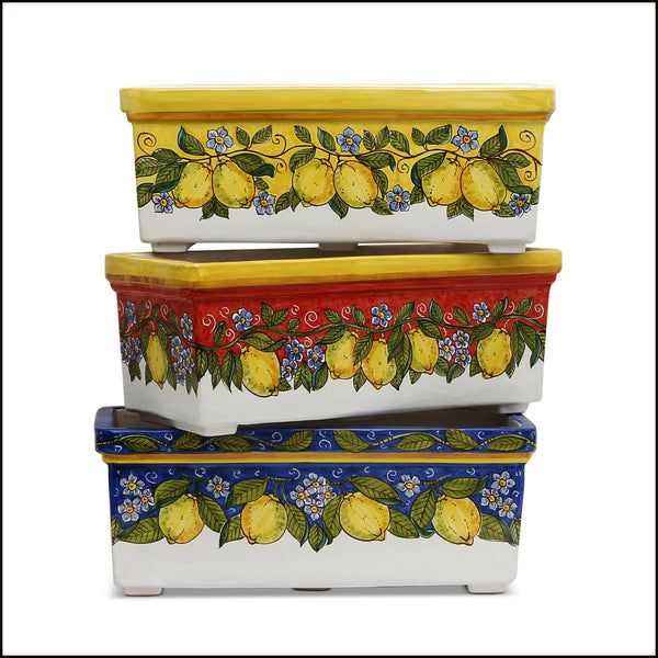 three ceramic containers with lemons and flowers painted on the sides, one is yellow