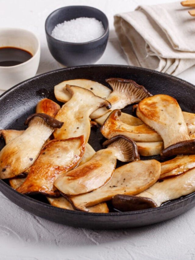 a pan filled with sliced mushrooms on top of a table next to two cups of coffee