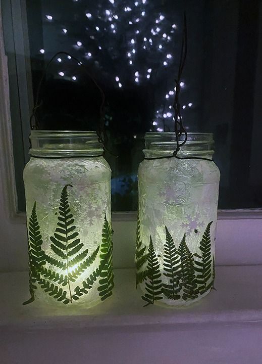 two mason jars with lights in them sitting on a window sill