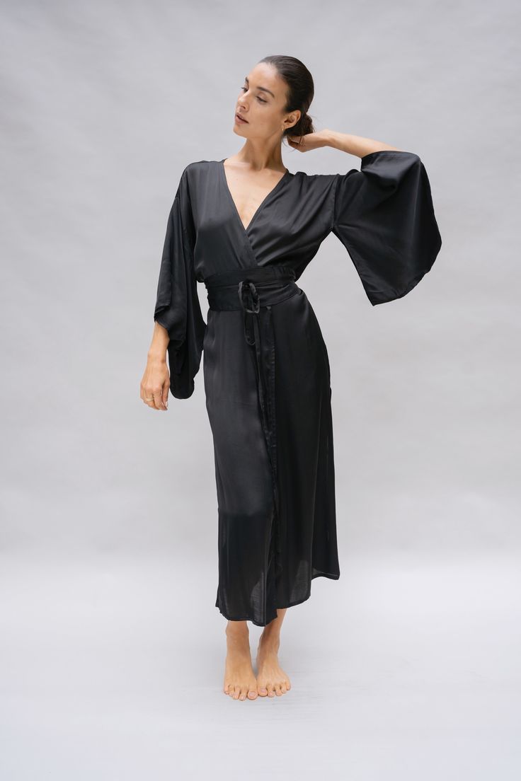 The Nerine Robe is an elegant wardrobe essential, showcasing an artful drape and dramatic sleeves. A tie waist belt accentuates your silhouette and the absence of belt loops allow for a versatile kimono jacket option. The Nerine robe is an elevated choice for morning and evening rituals, as well as any moment in between, whether you're at home or in a faraway destination. Elegant Belted Silk Wrap Dress, Chic Wrap Robe With Tie Waist, Fitted Wrap Robe, Elegant V-neck Belted Robe, Chic Kimono With Tie Waist And Kimono Sleeves, Elegant Wrap Dress With Tie Waist For Daywear, Elegant V-neck Kimono For Daywear, Chic Wrap Dress With Kimono Sleeves For Evening, Chic Evening Wrap Dress With Kimono Sleeves