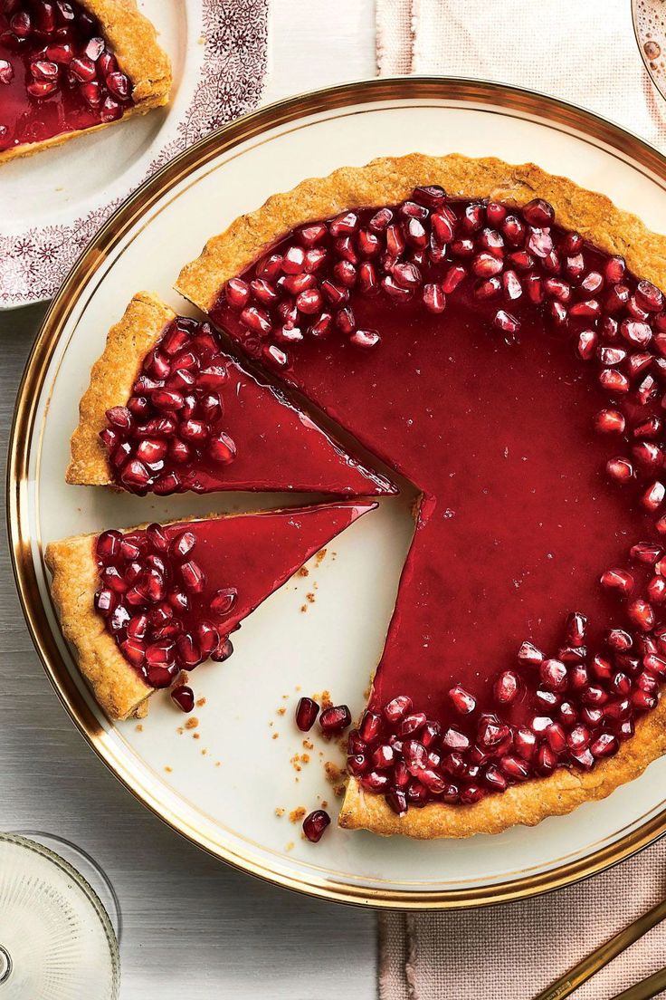 there is a pie with pomegranates on the plate next to it