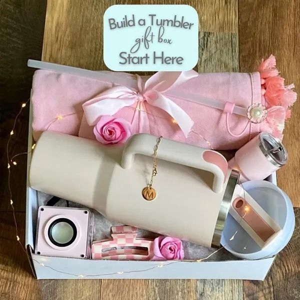 a pink gift box filled with lots of items on top of a wooden table next to a sign