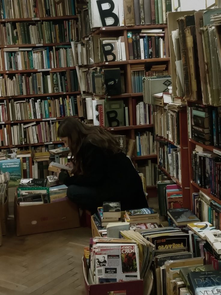 a woman sitting in front of a book shelf filled with books