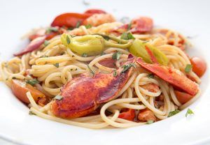 a white plate topped with pasta and lobster