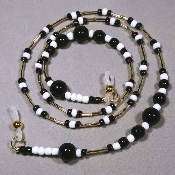 This eyeglasses chain is made with graduated sizes of round black glass beads, black and white glass seed beads and shiny gold colored bugle beads. The neutral colors will go with anything and will be a great gift for either a man or woman. Length - 28" (71.12 cm) Weight - 1.27 oz. (36 grams) Multi-strand stringing wire Silicone ends Handmade White Glasses Chains With Round Beads, Black Glass Beaded Jewelry, Black Glass Beaded Necklaces With Round Beads, White Beaded Glasses Chains With Round Beads, White Glasses Chains With Adjustable Round Beaded Chain, White Glasses Chain With Adjustable Round Beads, Black Glass Beaded Necklace With Round Beads, Handmade Glass Beads In Black, Handmade Black Glass Beads