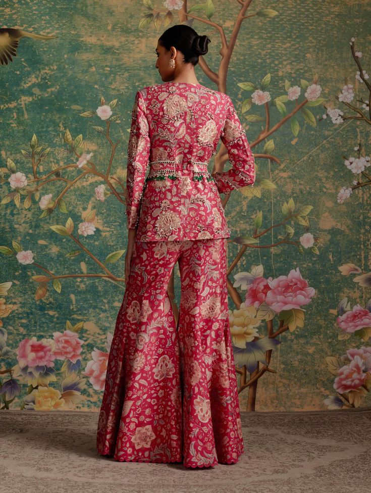 Upgrade your wardrobe with this pant suit set, featuring a printed raw silk embroidered jacket paired with printed flared pants and an intricately embroidered printed belt. The jacket boasts exquisite threadwork, pearls, green crystals, and gold sequins, adding a touch of glamour to the ensemble. This versatile set effortlessly transitions from formal occasions to special events, making it a wardrobe essential. Perfect for festivities and weddings, the combination of style and comfort makes it a Silk Indian Outfits, Banarsi Dress Designs, Banarsi Suit Design, Mehendi Dress, Suits For Women Indian, Pant Suit Set, Wedding Fits, Ridhi Mehra, Fusion Wear