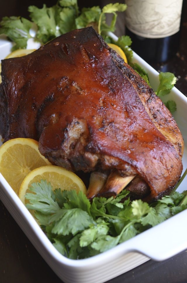 there is a large meat with lemons and parsley in the dish on the table