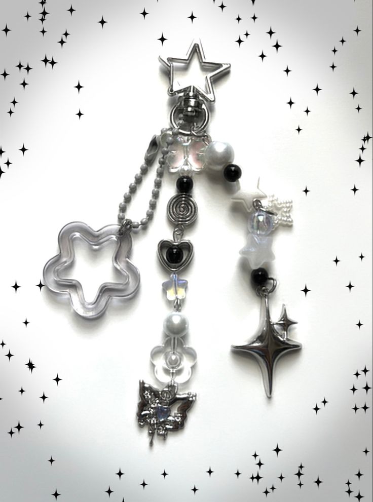 a silver necklace with black and white charms on it's side, surrounded by stars