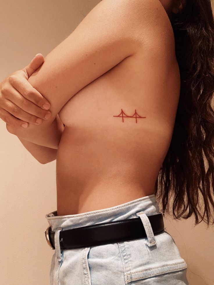 a woman with a small tattoo on her chest holding her arm up to the side