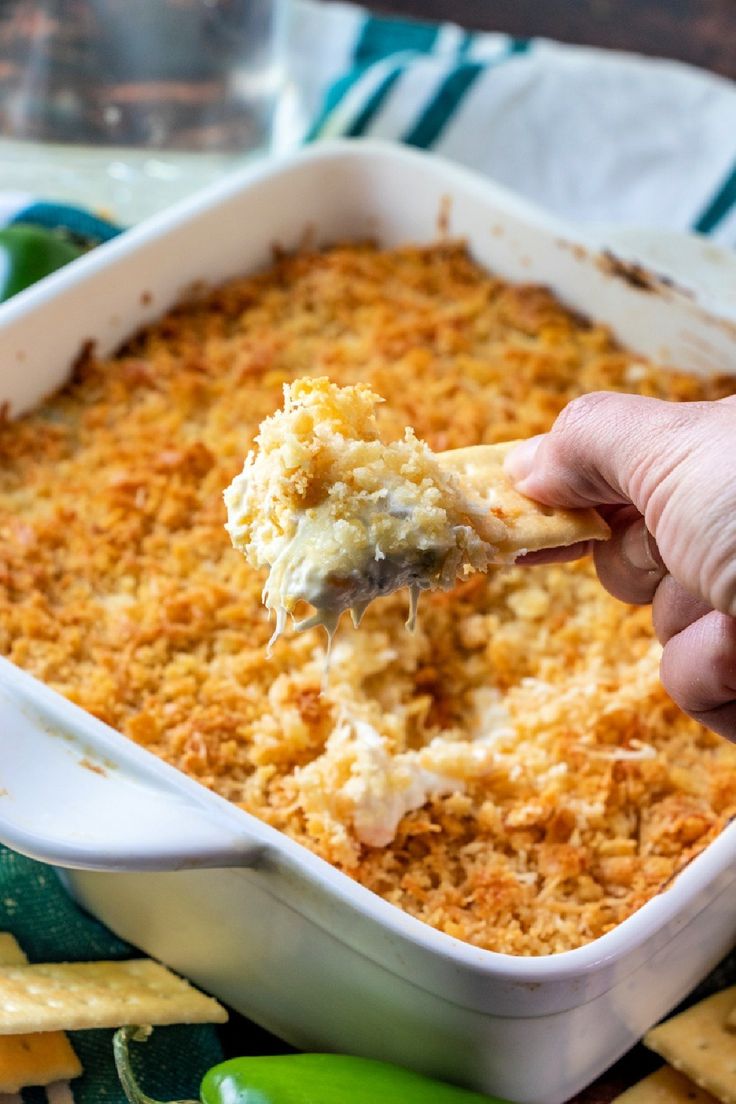 a person dipping some food into a casserole