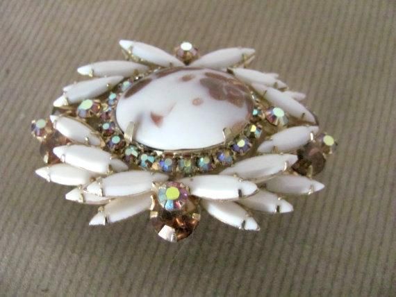 Gorgeous vintage milk glass and copper fluss Juliana brooch by D & E from the 1960's. Set in gold-tone metal are beautiful prong set milk glass navette stones, a center copper fluss stone, all surrounded by champagne colored rhinestone accents. Brooch is oval shaped and measures 2-5/8" x 1-3/4". Good vintage condition.  There is a slightly uneven edge on the bottom of the large center stone (see photo 2), but otherwise just a beautiful piece.For more vintage brooches, check out the Vintage J Vintage White Cameo Brooch, Vintage White Cameo Brooches, White Vintage Collectible Brooch, Vintage Rhinestone Brooch, Brooch Jewelry, Champagne Color, Rhinestone Brooches, Vintage Rhinestone, Gold Tone Metal