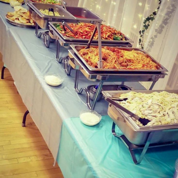 a buffet table filled with lots of different types of food on top of blue cloths