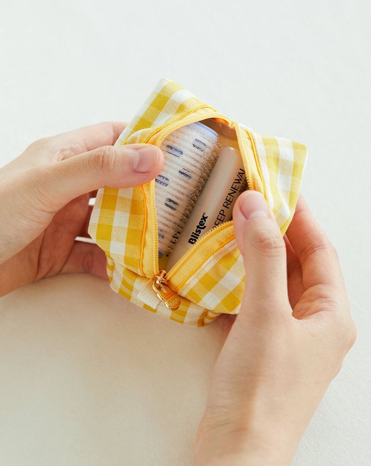 a person holding a yellow and white checkered cloth in their left hand, with a measuring tape sticking out of it