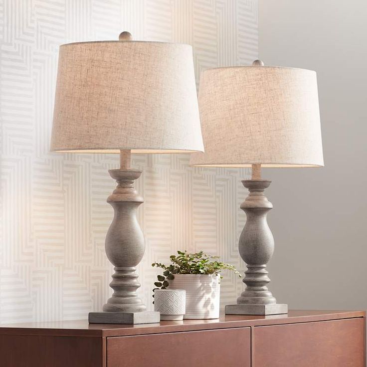 two lamps sitting on top of a dresser next to a potted plant and lamp shade