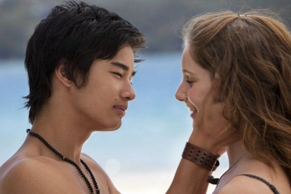 two people standing next to each other near the ocean