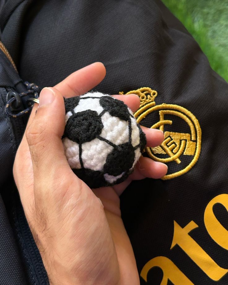 a hand holding a small black and white soccer ball in it's pocket,