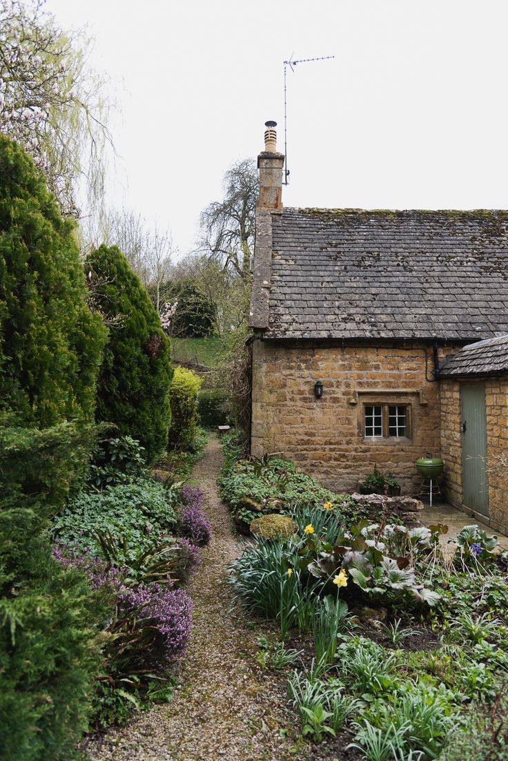 an old brick house surrounded by plants and flowers