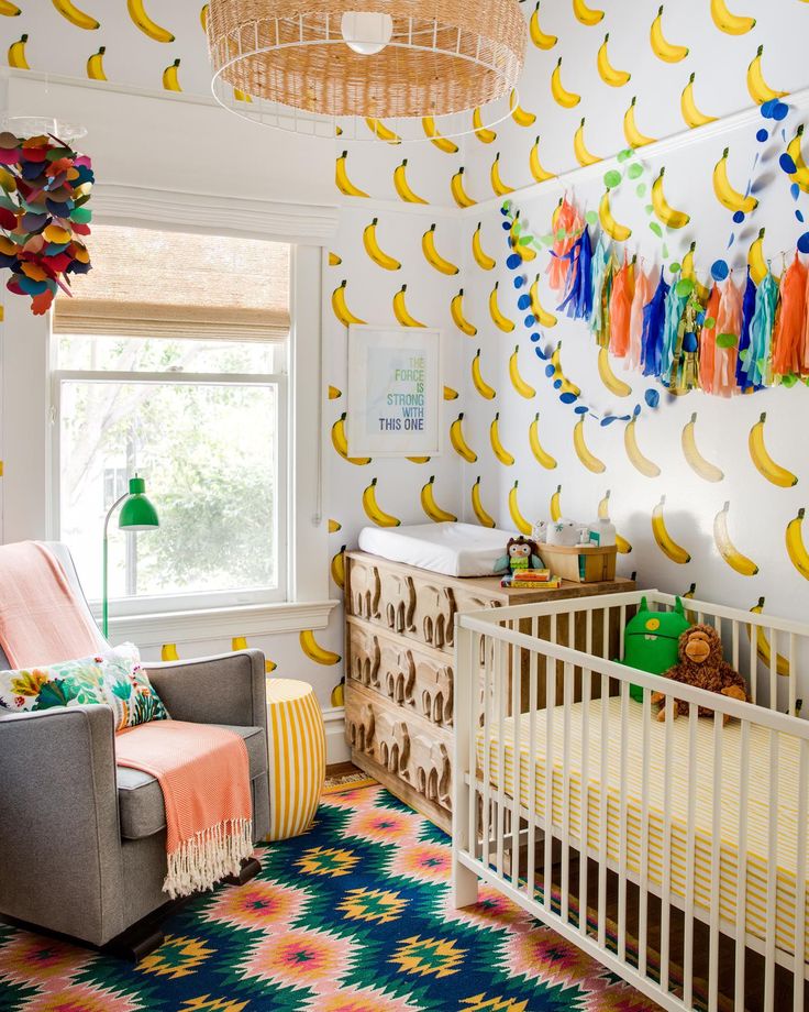 a baby's room decorated in bright colors with bananas on the wall and crib