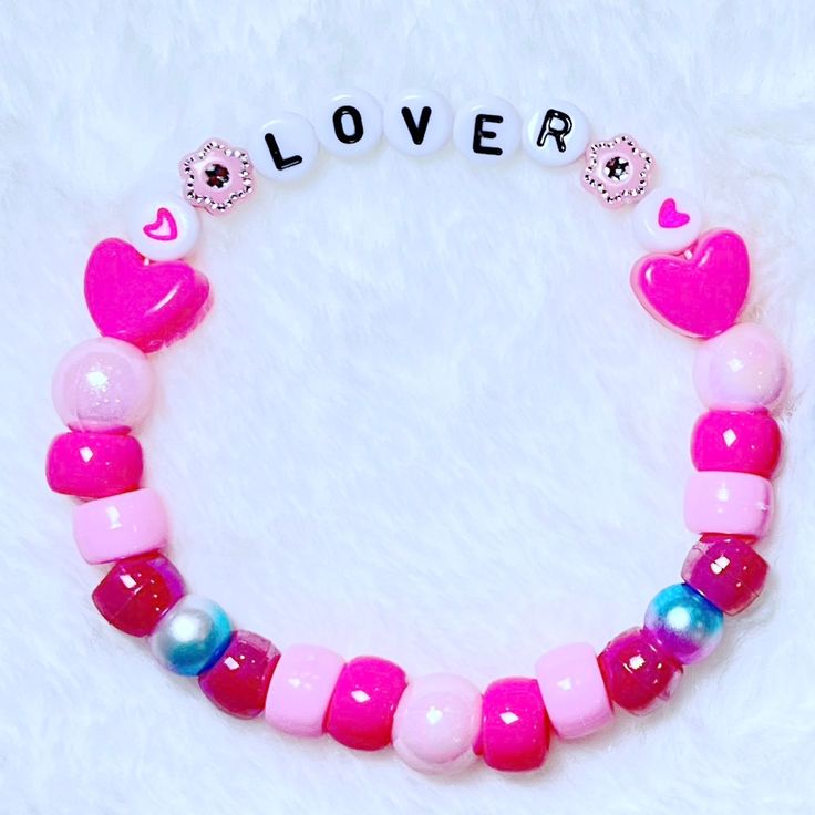 a pink and blue beaded bracelet with two hearts on it that says lover