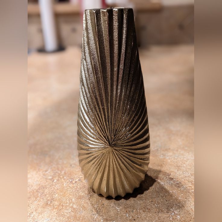 a gold vase sitting on top of a counter next to a white candle holder with an intricate design