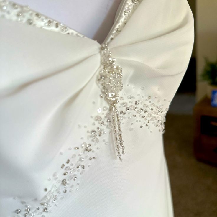 the back of a white wedding dress with beaded details on it's sash