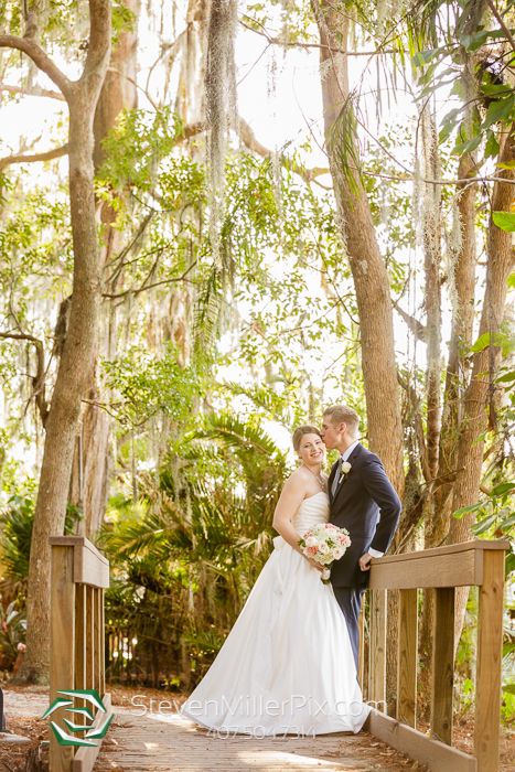 a bride and groom standing on a bridge in the woods