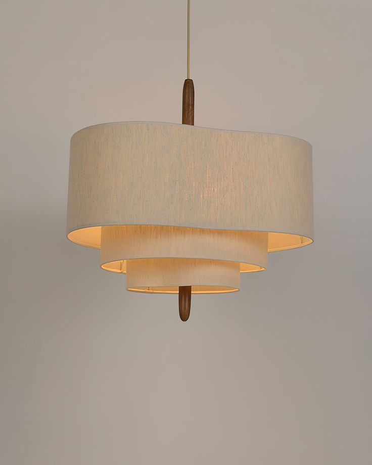 a white lamp hanging from a ceiling with a beige shade on it's side