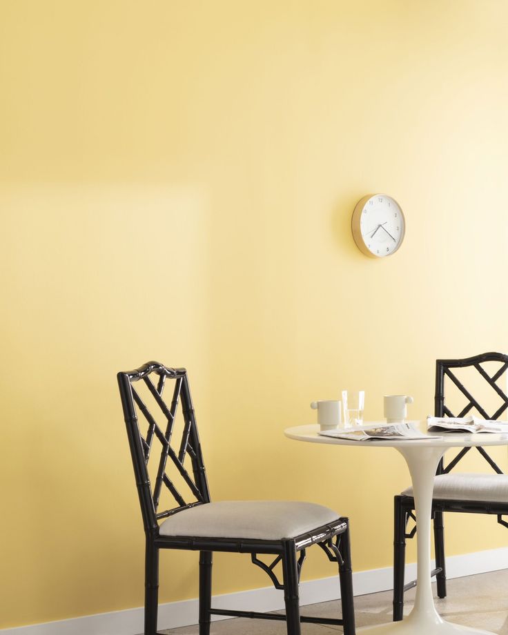 two chairs sitting at a table with a clock on the wall in the back ground