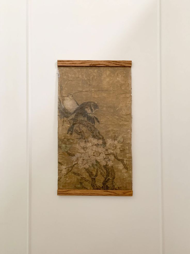 a painting hanging on the wall next to a wooden framed object with a bird flying over it