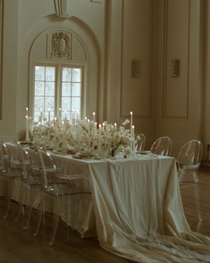 a dining room table is set with white flowers and candles for a formal dinner party