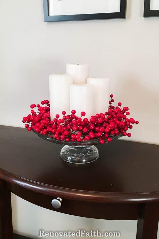 a table with candles and red berries on it