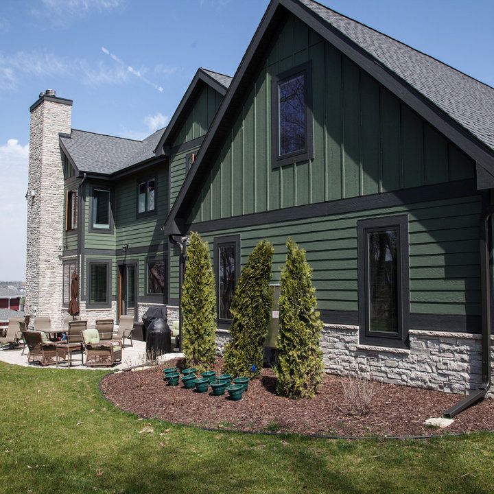 a large house with green siding and landscaping