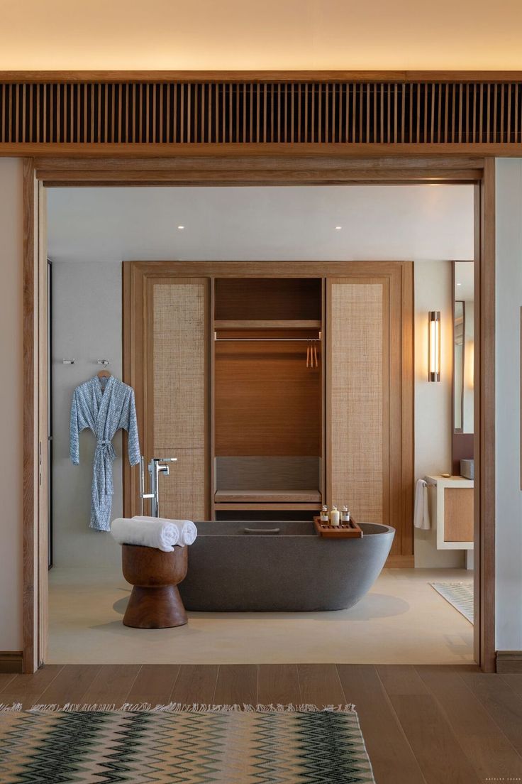 a bath tub sitting next to a wooden door in a bathroom under a light fixture