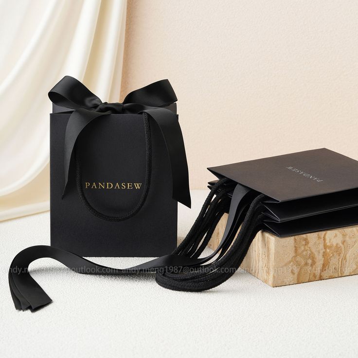 a black bag sitting on top of a wooden block next to a small box with a ribbon