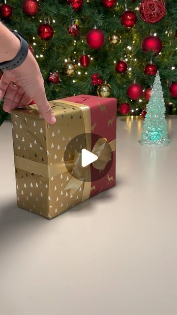 a person is opening a gift box in front of a christmas tree with presents on it