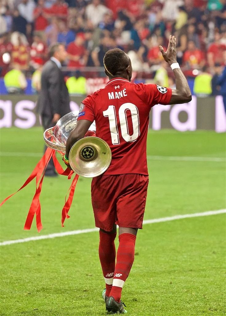 a soccer player is walking off the field with his trophy