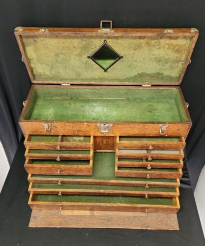 an old wooden box with many drawers and compartments in it's lid, on a black background