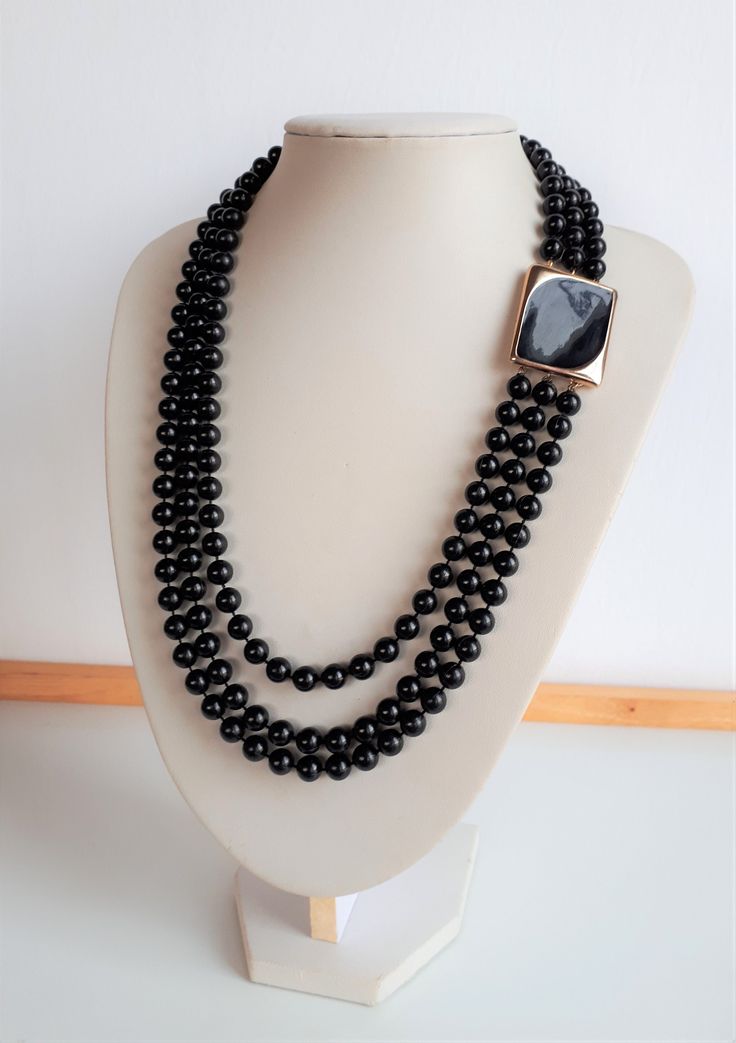 Elegant and chic MICHELE LYNN signed black lucite plastic 3 graduated rows beaded necklace with big gold and black modern rectangular shape enamel clasp. Signed on the clasp on the back. Good condition. Longest row: 23 inches; shortest row: 19.5 inches; beads: 7 mm; clasp: 1-3/8 x 1-1/8 x 1/8 inches.  IMPORTANT TO READ: To make this a smooth and pleasant transaction experience for everyone, all buyers need to read and understand the description, the terms of sale , the payment and the shipping indicated in this listing. TERMS OF SALE A. SHIPPING WORLDWIDE This listing includes payable tracked services with the fees indicated below. B. CARRIERS We don't ship with FedEx, DHL or UPS or any other carrier except for Canada Post unless a specific agreement with the buyer is accepted by us at our Black Enamel, Stone Bracelet, Necklace Gold, Gold Black, Costume Jewelry, Jewelry Inspiration, Etsy Vintage, Favorite Jewelry, No Response