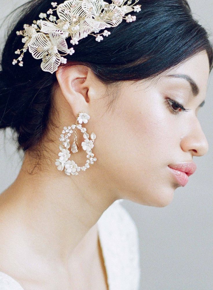 a woman in a white dress wearing a head piece with flowers and pearls on it