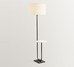 a floor lamp with a white shade on it and a black stand next to it